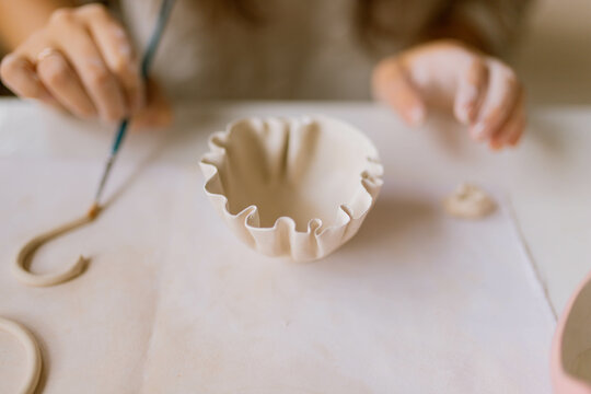 young woman makes ceramic dishes in the workshop