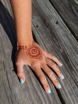 Young girl hand with Henna Tattoo wood background