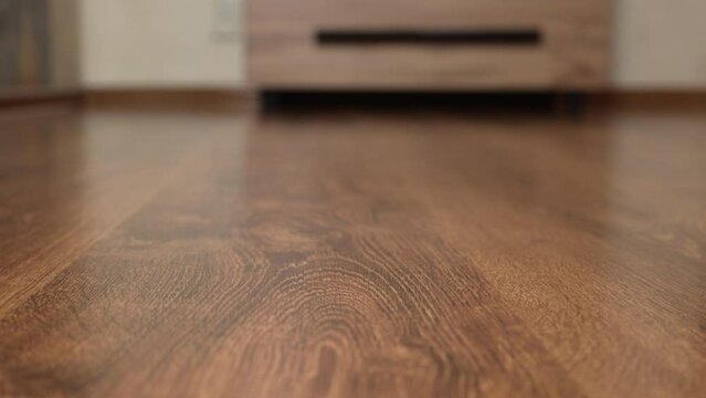 Texture of brown wooden parquet floor with natural pattern close-up. Forward movement. Treated wood texture. High quality 4k footage. 