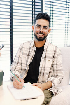 Smiling entrepreneur drafting plans in bright office