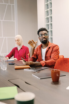Thoughtful worker gesturing meeting colleague writing notes