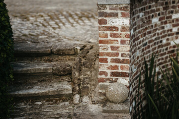 Brick wall with stone sphere by purple flowers