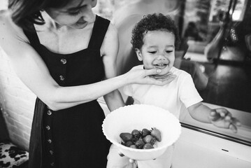 mother feeds her son with strawberries