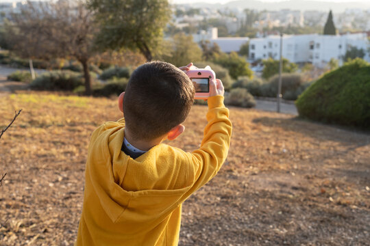 Child Capturing Sunset With Camera Outdoors.