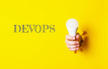 A person holding a light bulb with the word Devops written underneath