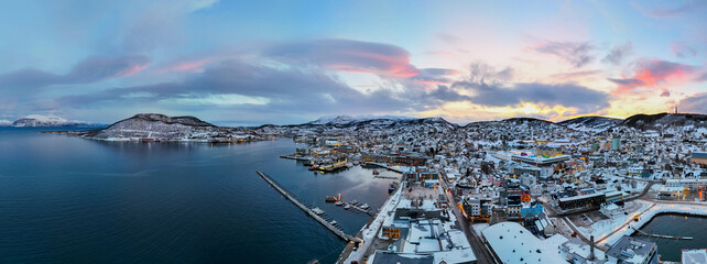 a beautiful snowy evening in a large harbor with buildings and a dock