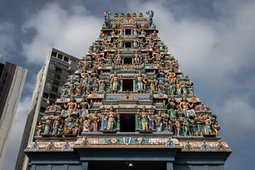 colorful hindu - like temple, with figures and windows against a cloudy sky