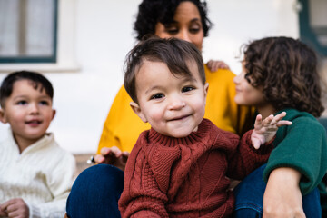 Brunette mother and her adorable three boys play lovingly while sitting outside