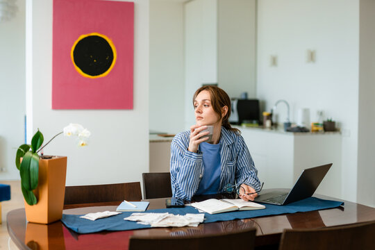 A woman drinks coffee working at home