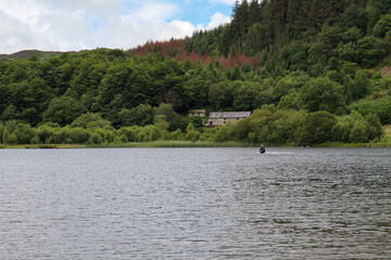 Serene lake with rural structures on the shore surrounded by lush greenery