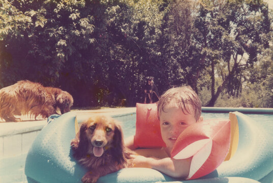 Young kid in the pool with his dog