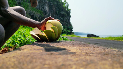 An African man cutting a coconut,