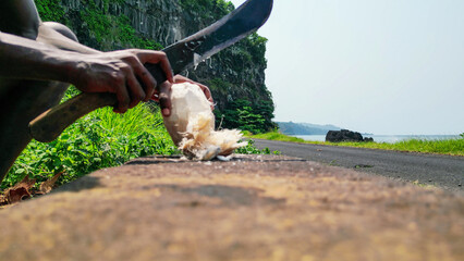 An African man cutting a coconut,