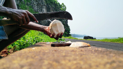 View of an African man with a machete cutting a coconut.