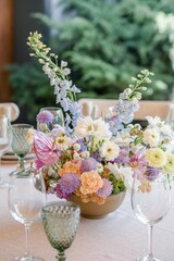 a vase of flowers with some wine glasses on a table