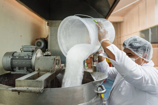 Man adding sugar into industrial pot at a food factory