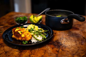 this meal has a fishcake on top of rice and green beans