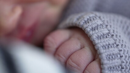 Macro close-up of newborn baby face and tiny hands during first days of life. Infant during his...