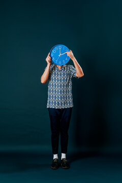 man standing on a blue background resets a blue clock