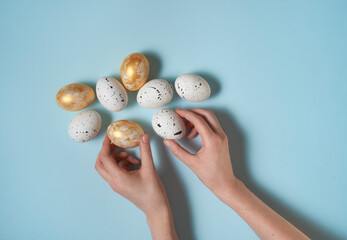Hands reaching easter eggs on pastel blue background