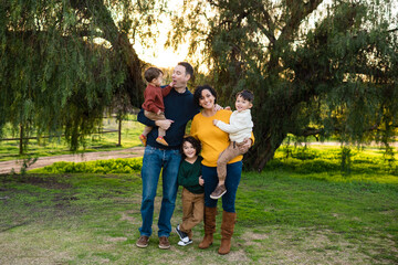 Young family smiles outside at sunset while embracing each other lovingly