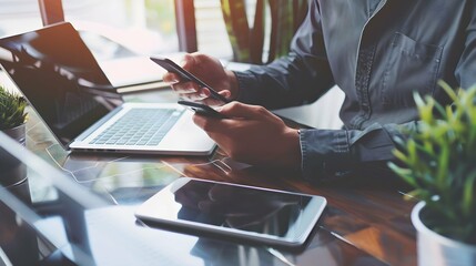 Businessman using mobile phone during working on laptop computer with digital tablet on office desk. Business man, project manager thinking, planning new business project