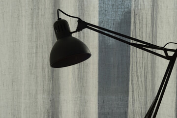 A classic reading lamp against a linen curtain background. Home comfort. Cozy lighting.