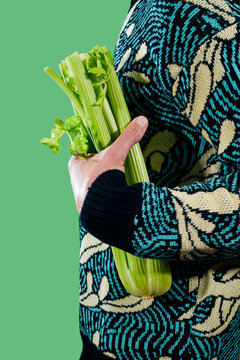 man carries a celery bunch under his arm