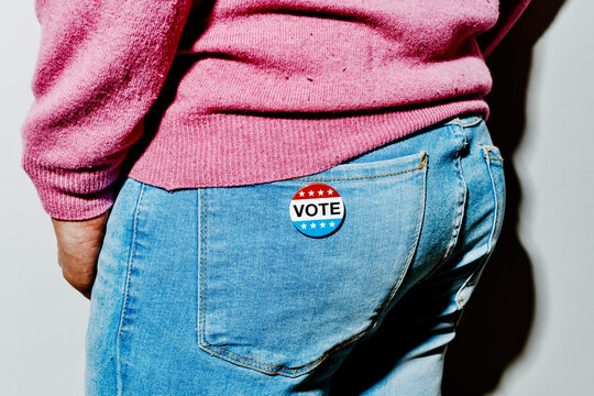 man wearing a US vote badge in the back pocket of his jeans