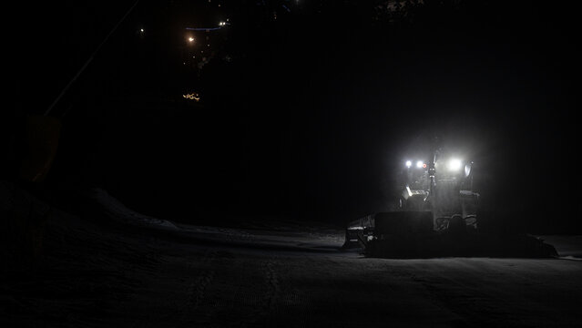 Snow-groomers work in nighttime on ski resort.