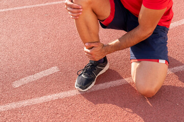 Athlete with injured ankle is holding his knee. knee and foot joint injuries