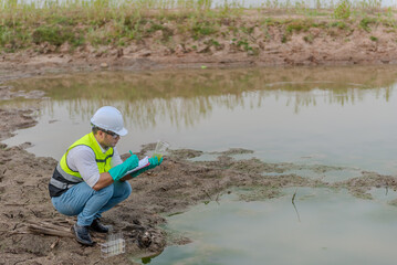 Environmental engineer Sit down next to a well while holding the plastic glass in his left hand and...