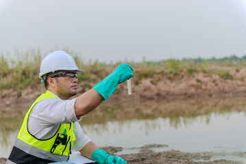 Environmental engineer Sit down next to a well while holding an experiment tube that fill with the...