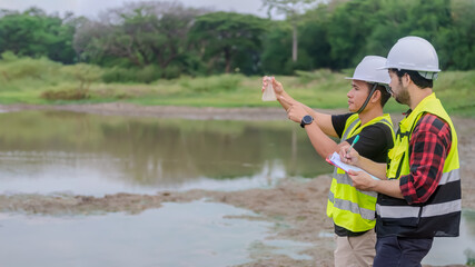 Two of environmental engineer stand next to a well while holding an experiment tube that fill with the water sample and check water quality and contaminants in the water source.