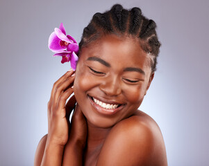 Skincare, flower and black woman in studio with natural, health and facial routine. Beauty, wellness and African model with orchid plant for dermatology face treatment with glow by gray background.