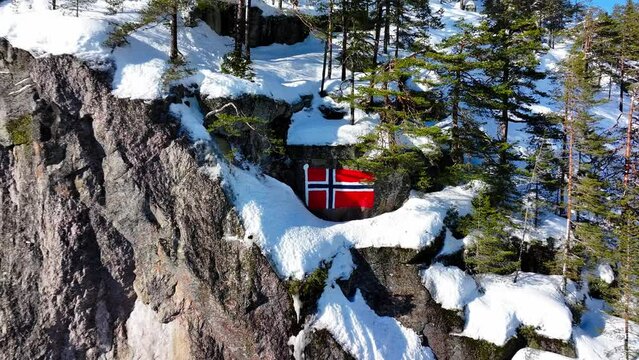 Drone pullout revealing Norwegian flag in snow-covered mountain hillside of Etnedal, Oppland, Norway