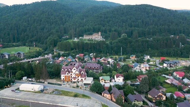 Aerial shot of the buildings of Busteni town with Cantacuzino Castle in distance in Prahova, Romania