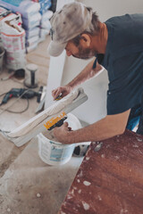 Worker puts putty on a spatula for plastering internal walls in a living room. plasterer works...