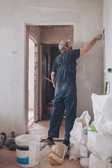 Plasterer using a finishing trowel to smooth new plaster on the surface of a wall in a house...