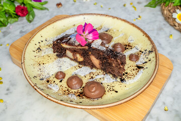 a chocolate dessert on a yellow plate with flowers in the background