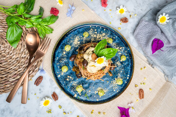 spaghetti dish served on a blue plate with herbs and flowers