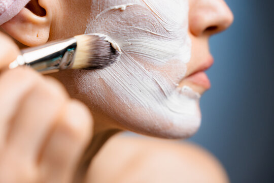 A woman applies a cosmetic mask to her face