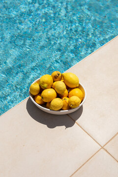 bowl with lemons on the edge of a swimming pool