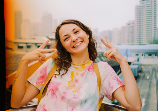 Cheerful woman showing peace gesture with colourful nails 