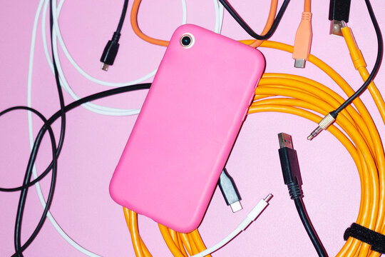 Tech curvy wires & smartphone a pink office desk with hard flashlight
