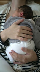 Newborn baby asleep on mother's chest being held by maternal love, close-up hands holding infant during first days of life, vertical video