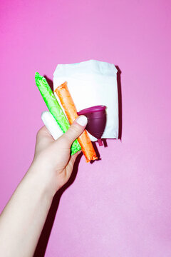 Hand holding different size period tampons with hard direct flashlight