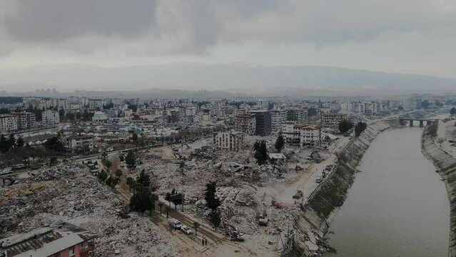 Drone over collapsed buildings after the earthquake in Hatay, Antakya with gray cloudy sky at sunset