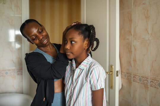 black mother with little daughter in the bathroom combing her hair