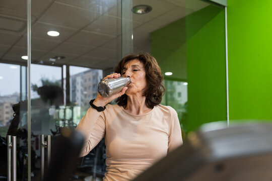 Mature woman hydrating at gym
